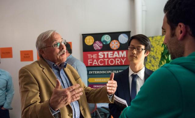 man speaking to two other men