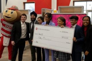 brutus buckeye and group of students with large fake check
