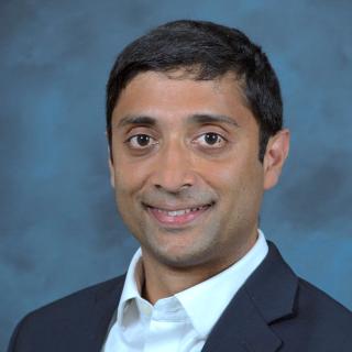 headshot of man in dark suit and white shirt