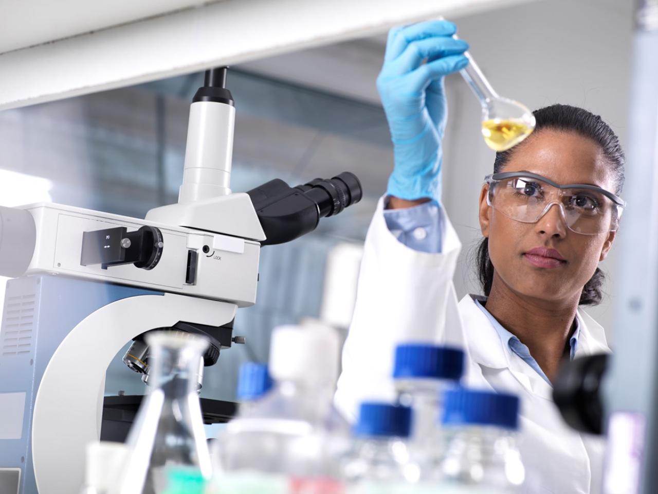 woman holding beaker of liquid in lab