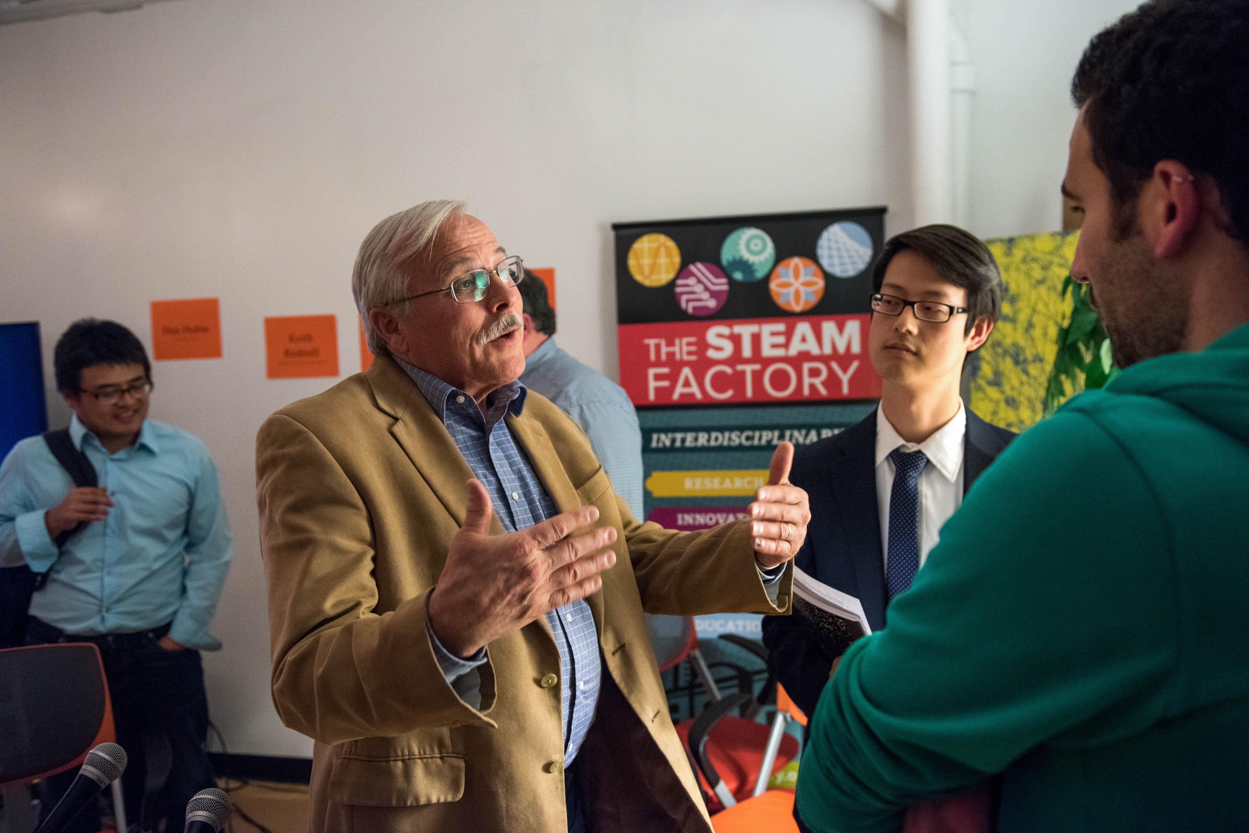 man speaking to two other men
