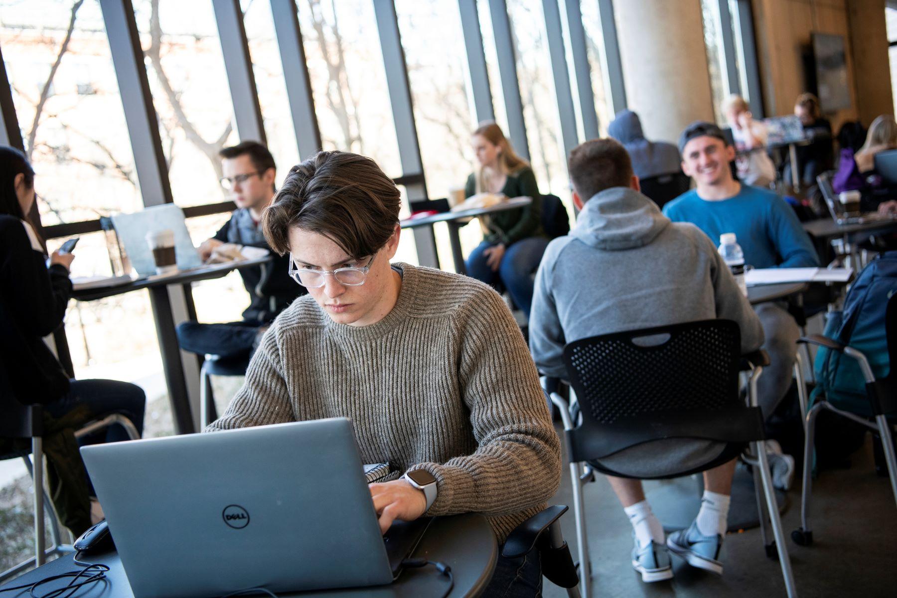 man on computer in a room full of other people