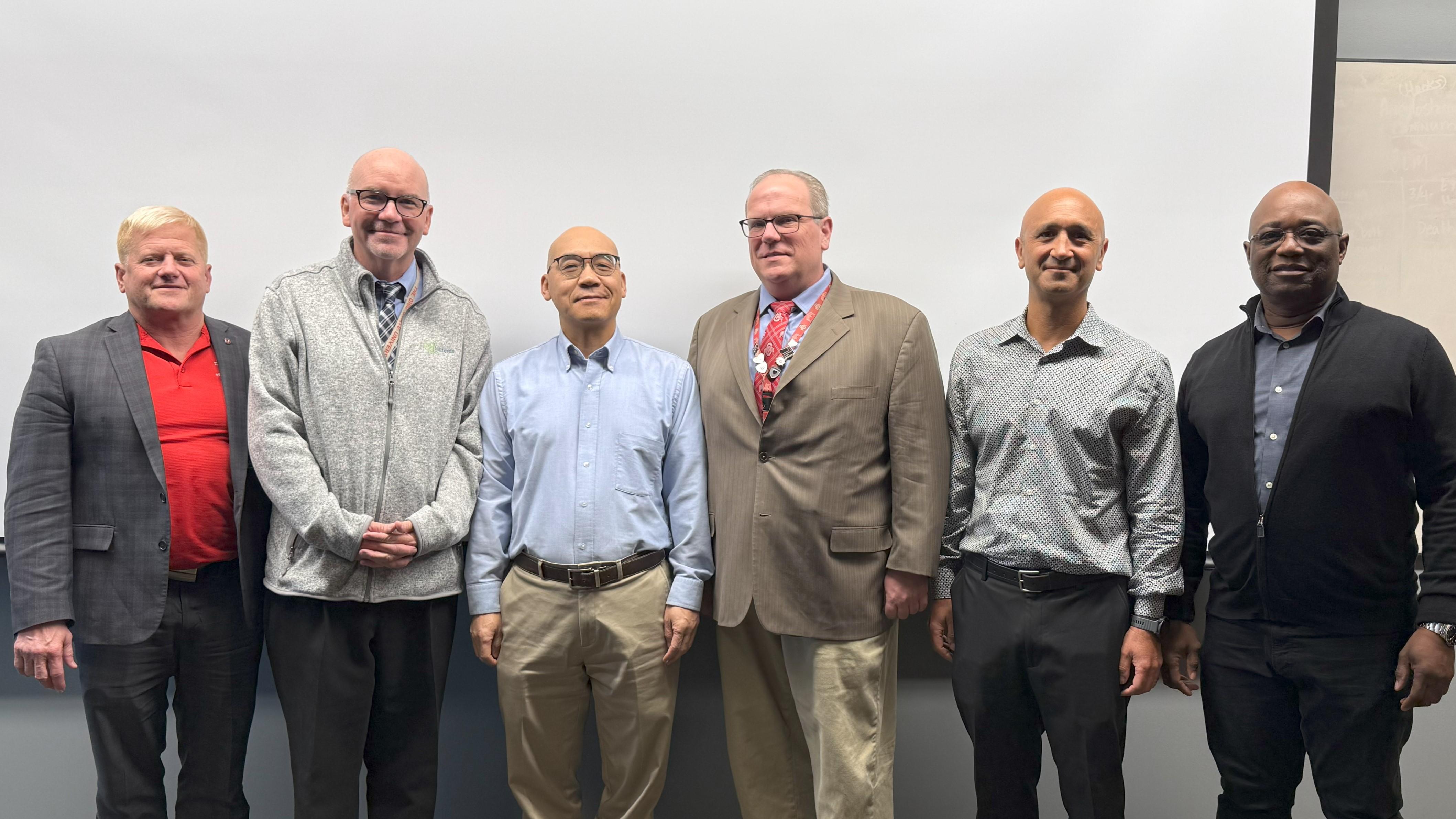 Six men standing in front of a whiteboard